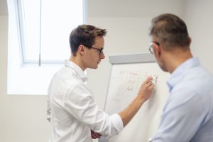 Two businessmen discussing at flip chart in office